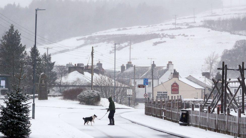 A man walks his dog through snow in Overwater, Cumbria, as five weather warnings are in place as heavy rain and snow blight swathes of the country on Easter Monday.