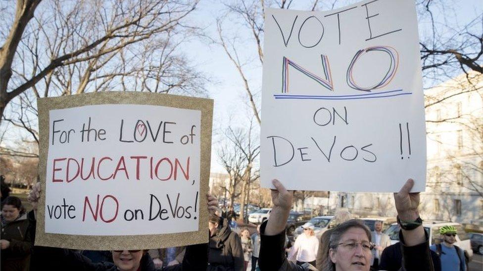 People hold signs during a rally calling for the US Senate to vote against confirming Betsy DeVos, President Donald Trump's nominee for Secretary of Education.