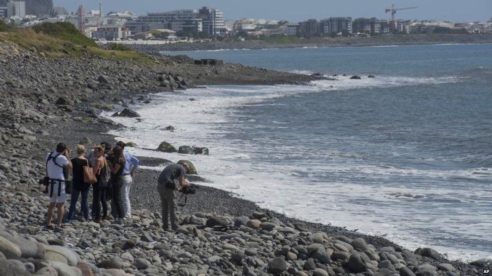 People in Reunion search a beach for possible plane debris near the shore where a wing part was washed up (02 August 2015)