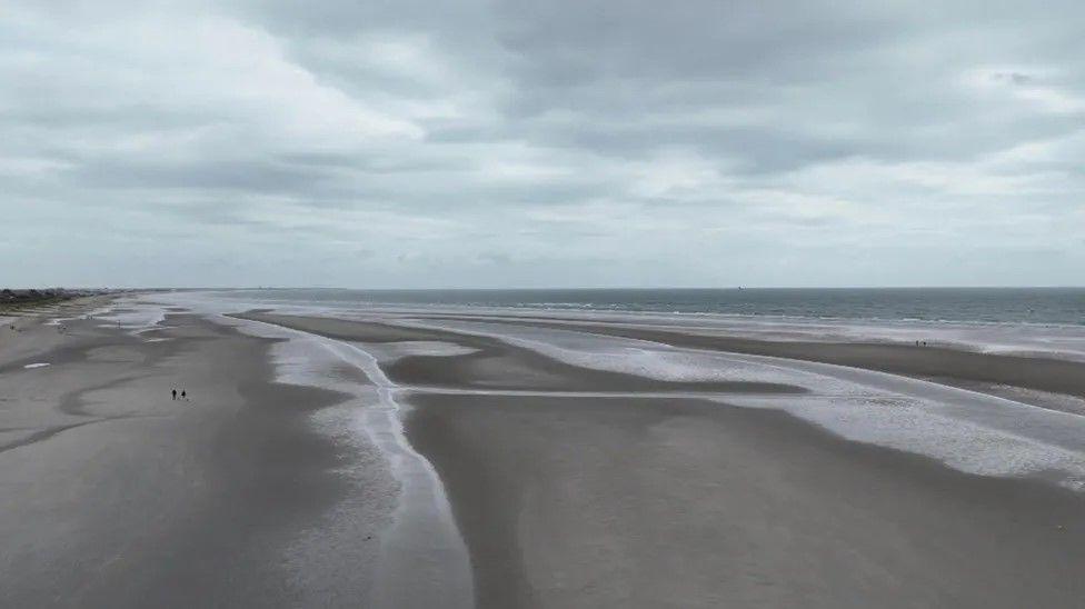 West Wittering beach at low tide. The sky is overcast.