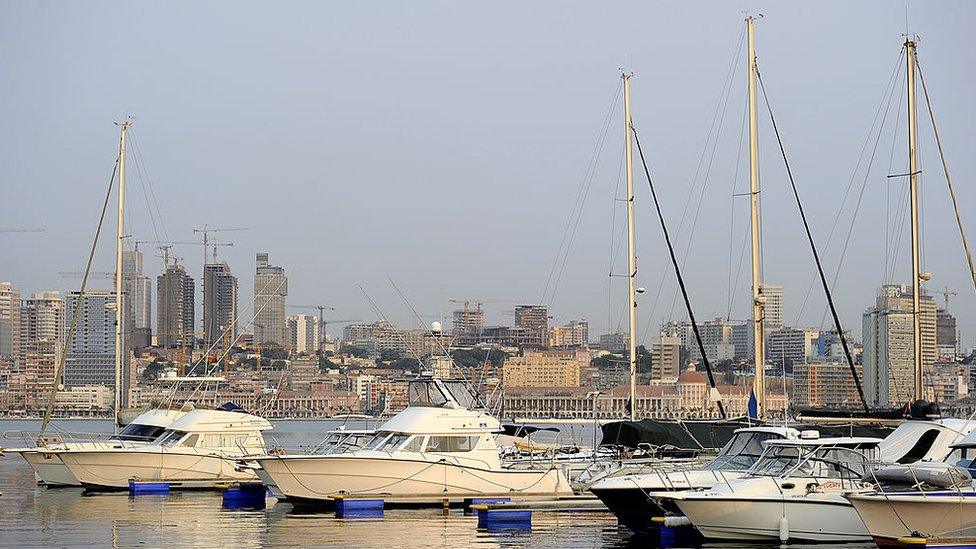 Boats are docked in a marina with Luanda's skyline behind