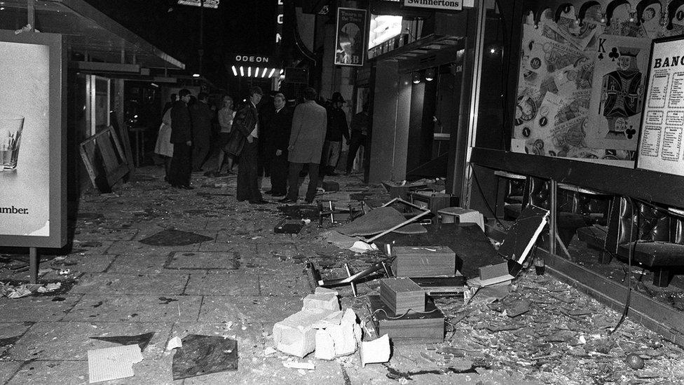 People stand by the remains of a shop front and bus shelter, damaged in one of the explosions, New Street, 21 Nov 1974