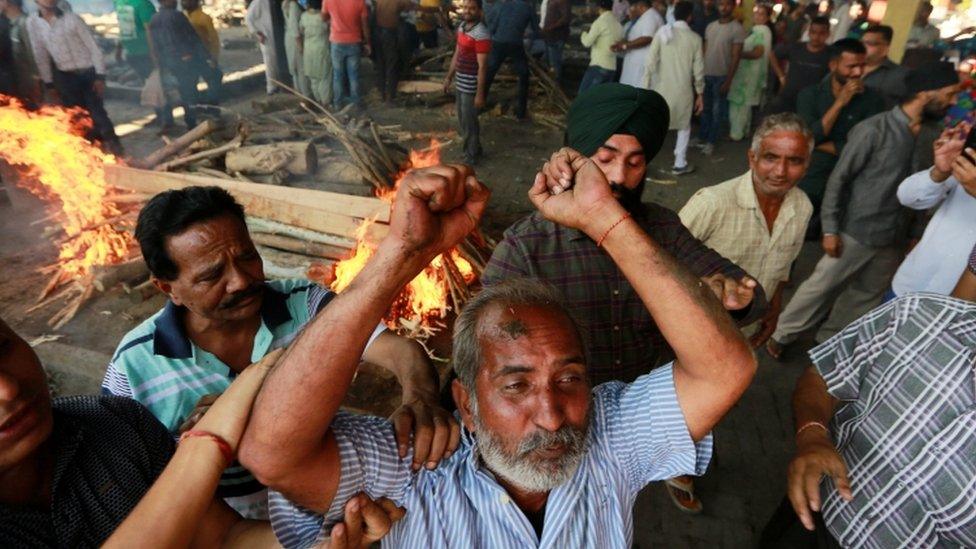 A man mourns near the pyre of a family member