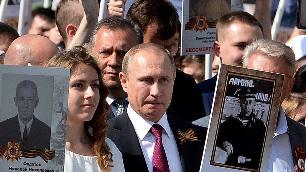 Russian President Vladimir Putin (C) carries a portrait of his father Vladimir as he takes part in the Immortal Regiment march in Moscow on May 9, 2016