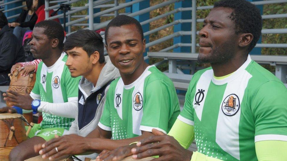 Team captain Darius (centre) and founder Medard (right) sit next to two other football club players