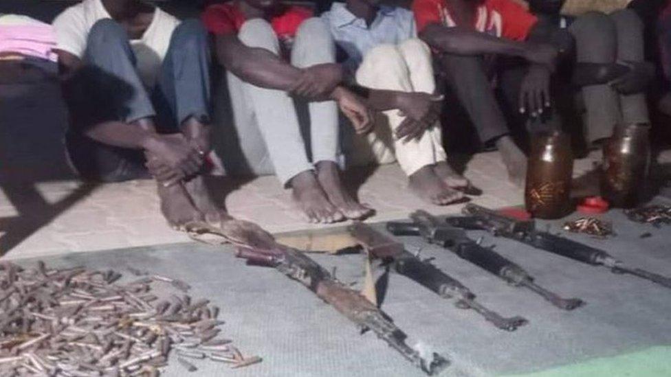 Detainees from Darfur seated next to weapons and bullets