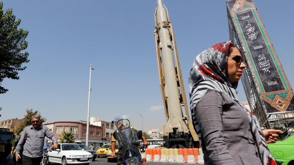 A woman walks past a Shahab-3 ballistic missile and launcher on a street in Tehran, Iran, during Defence Week (26 September 2019)