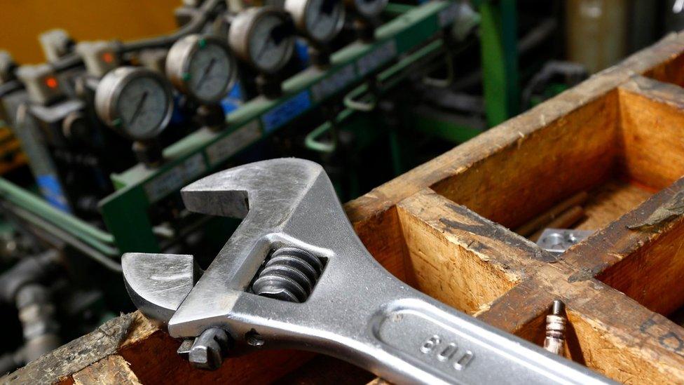 A wrench lies on a workbench at manufacturing firm