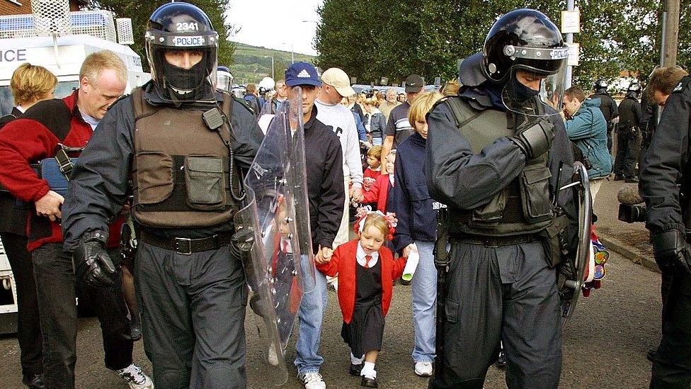 Police officers in riot gear escorted schoolgirls and their families past the protesters