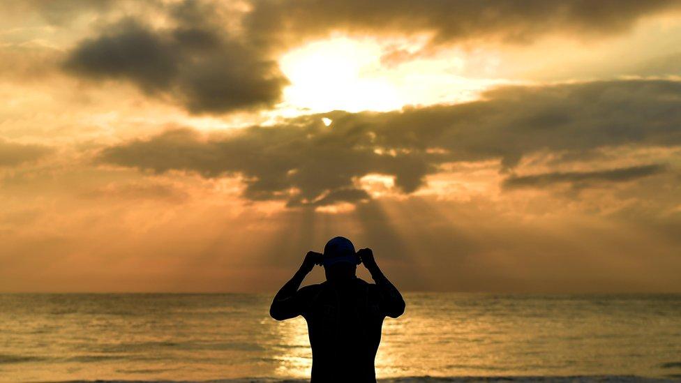 A tri-athlete putting on goggles on a beach in Port Elizabeth, South African - Thursday 30 August 2018