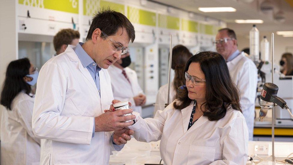 Natasha's parents examine a beaker while dressed in lab coats and protective glasses in a lab at Southampton University