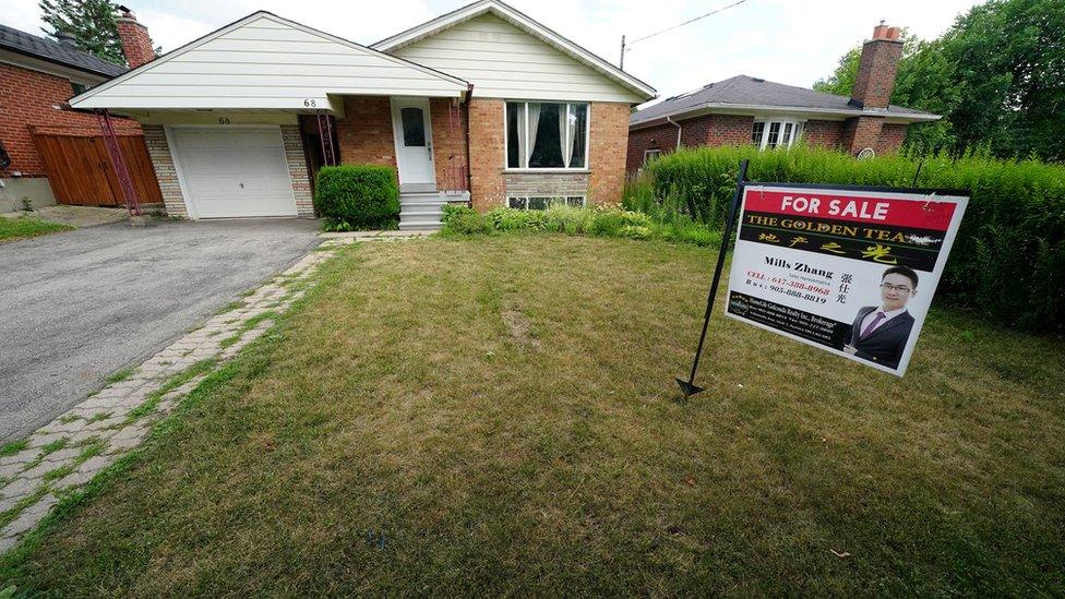 "For Sale" sign is pictured in the front yard of a house in Toronto, Ontario, Canada