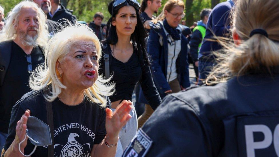 A woman shouts in front of a police member during a protest against the government measures to curb the spread of the coronavirus disease