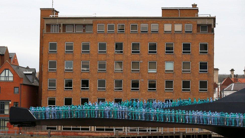 Naked people painted blue on a bridge