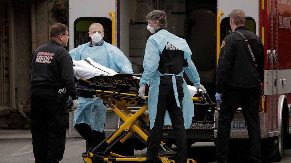 Medics prepare to transfer a patient on a stretcher to an ambulance at the Life Care Center of Kirkland