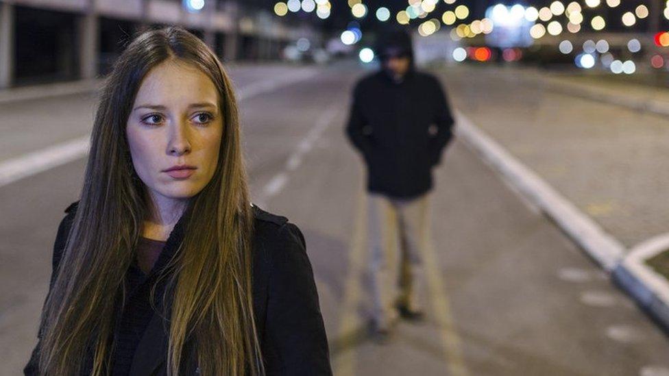 Woman being followed by a man down the street