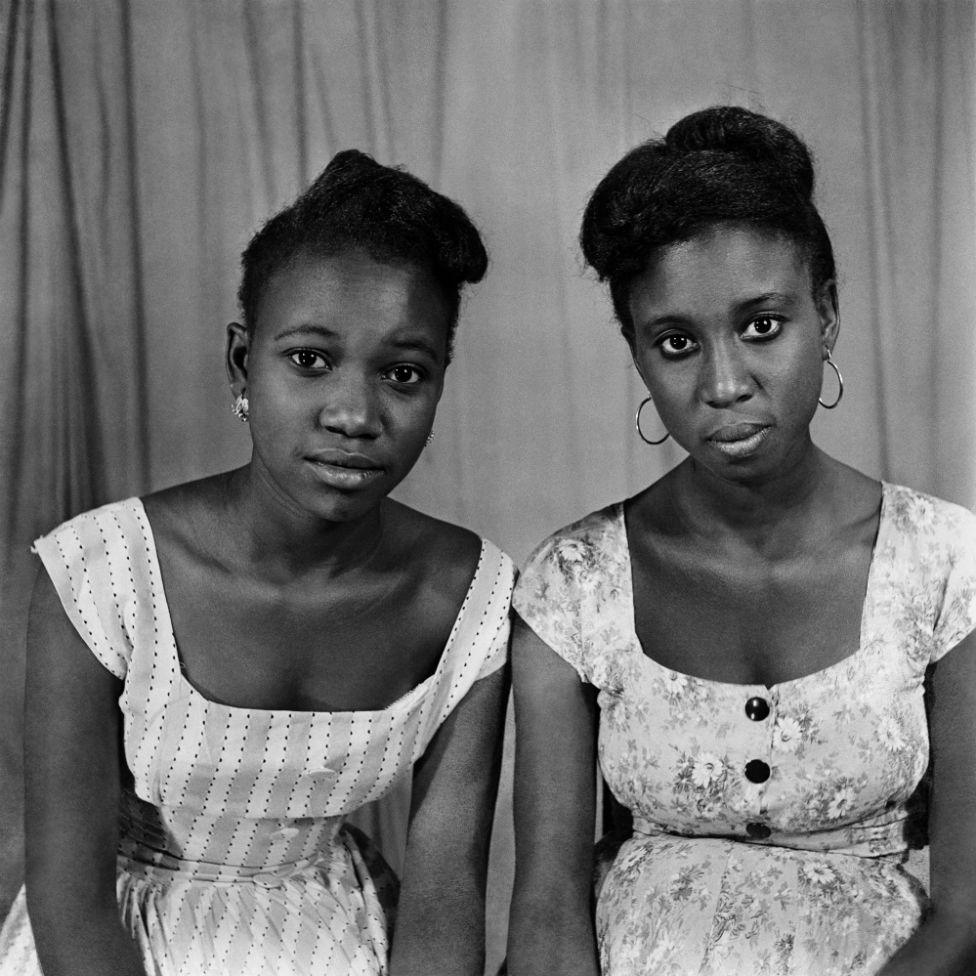 Two women pose for the camera in the photographer's studio.