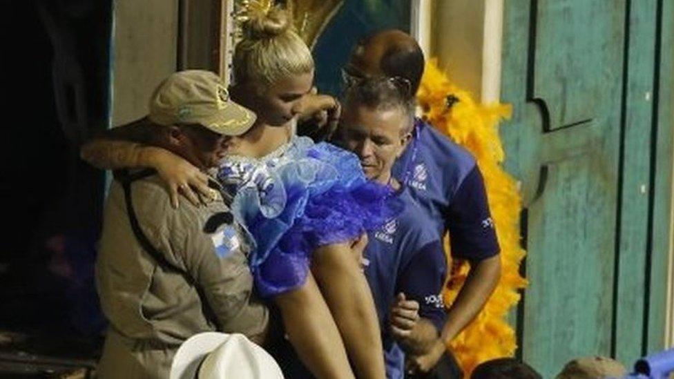 Firefighters carry a woman from a float during the performing of the Unidos da Tijuca samba school for the Carnival celebrations at the Sambadrome in Rio de Janeiro, Brazil, Tuesday, Feb. 28, 2017