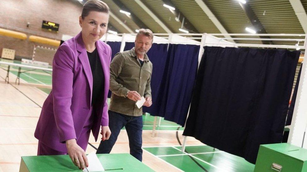 Danish Prime Minister Mette Frederiksen, also leader of Denmark's Social Democrats, casts her ballot as her husband Bo Tengberg looks on at a polling station in Vaerloese near Copenhagen, Denmark, on June 1, 2022