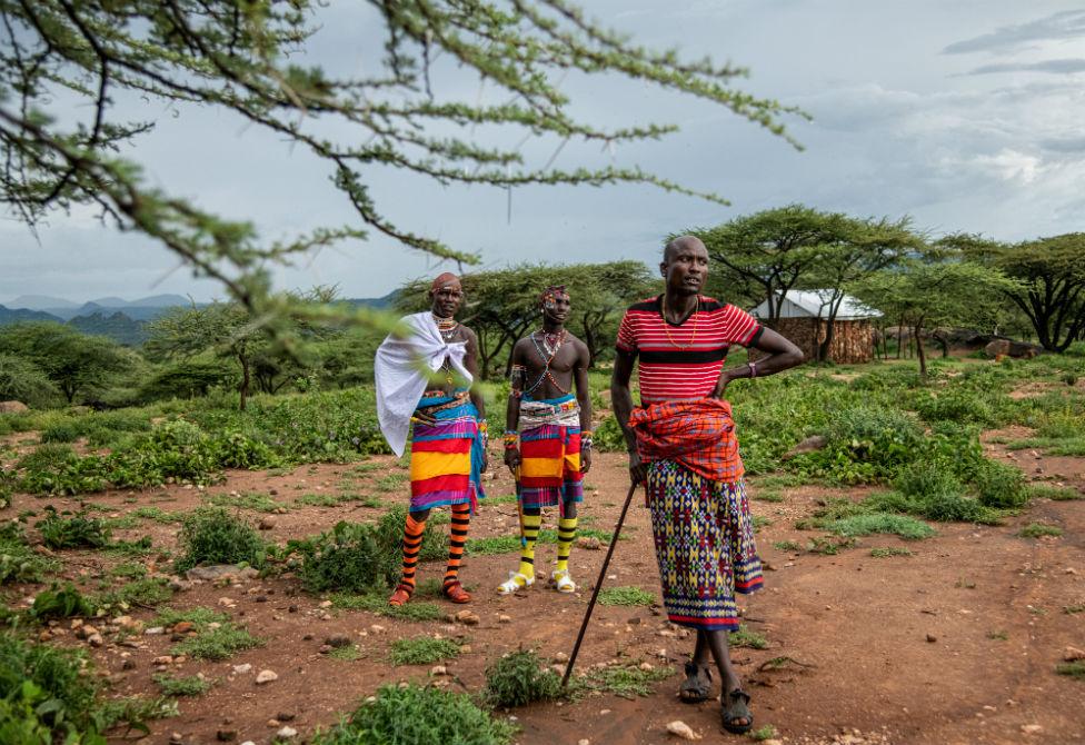 Two Samburu warriors talk to Tiampati Leletit, who lost 80 of his goats when the locusts arrived