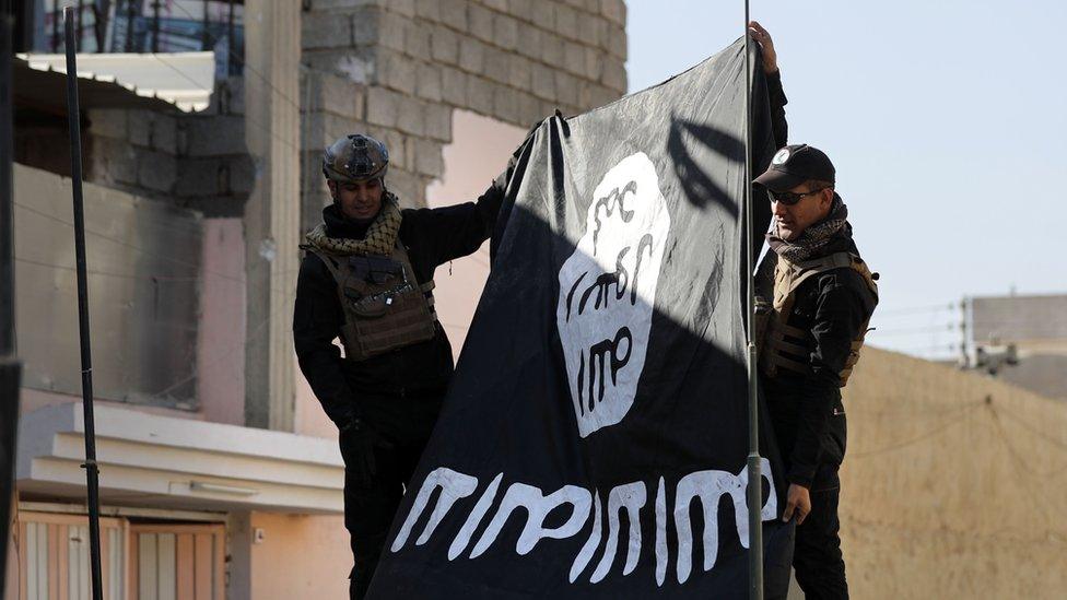 Soldiers from the Iraqi army hold an IS flag upside down in a north-east district of Mosul