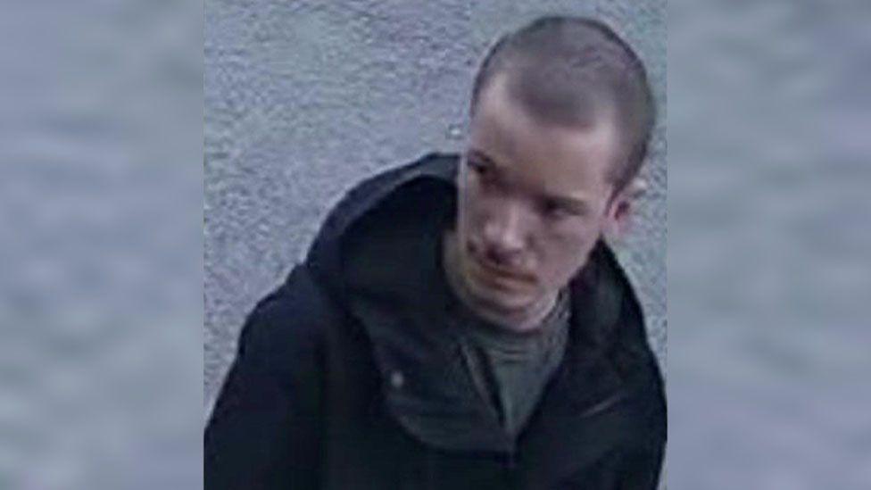 CCTV image of Sam. He has short dark hair and is wearing a dark jacket