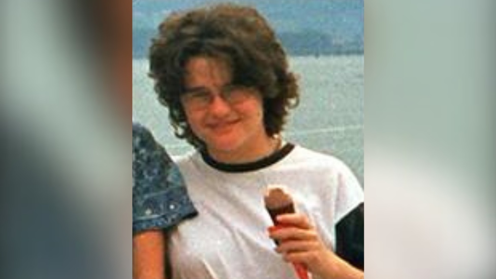 Young woman wearing a wearing a white t-shirt and glasses holding an ice cream. 