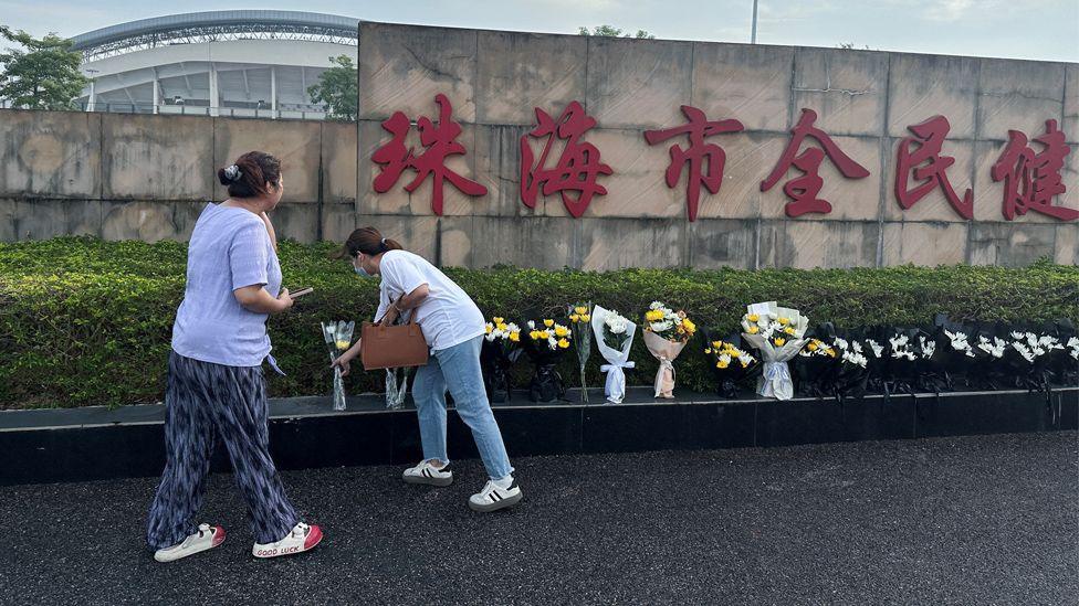 Two women place flowers outside the stadium in Zhuhai after the attack