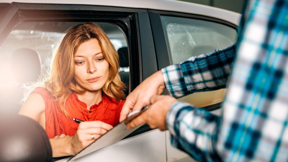 Woman signs car rental agreement