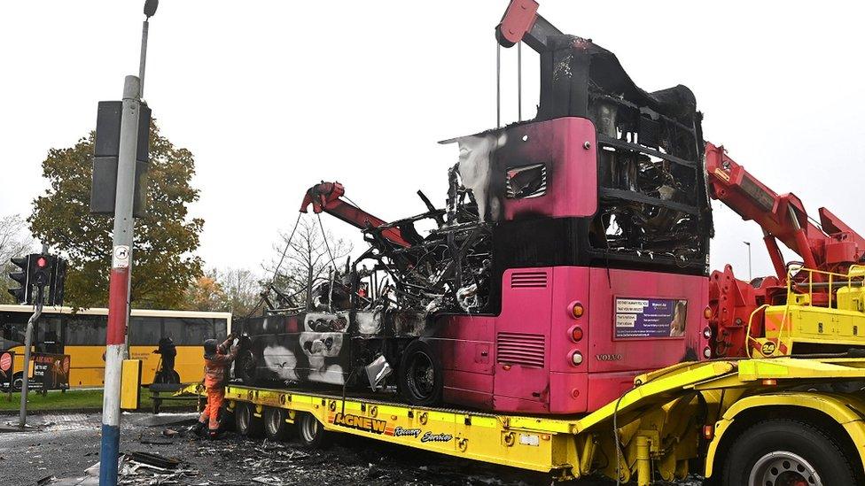 The wreckage of the burnt bus being lifted on to a lorry in Newtownabbey