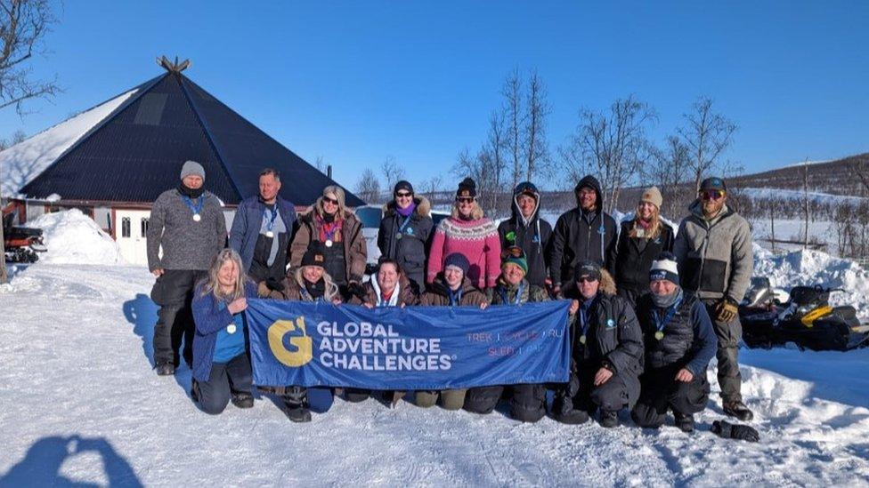 A team of partcipants pose with a banner saying 'Global Adventure Challenges'