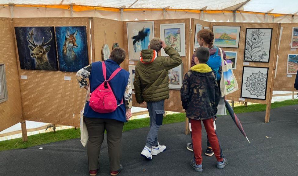 People looking at paintings being displayed at the event