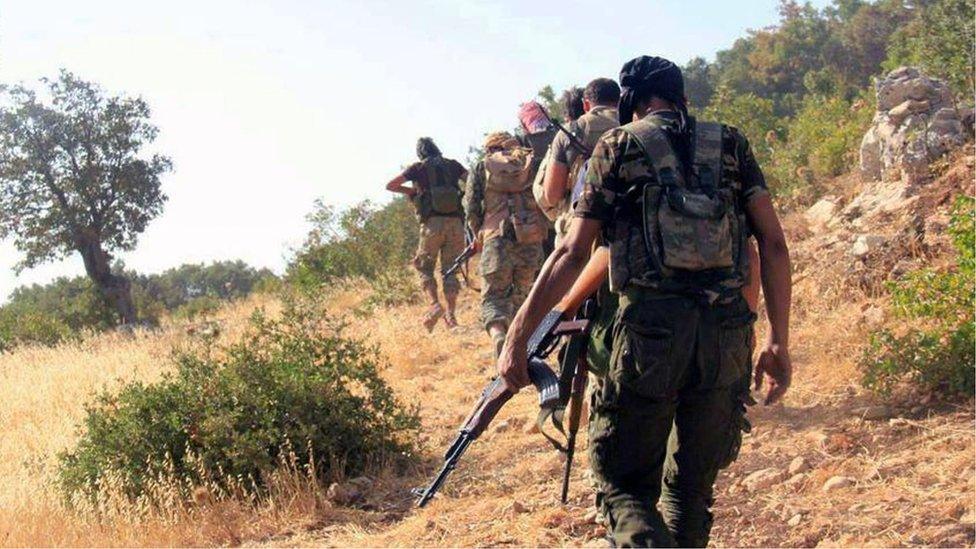 Rebel fighters from Ahrar al-Sham walk towards Syrian army positions in the Jabal al-Akrad region of Latakia province (13 September 2015)