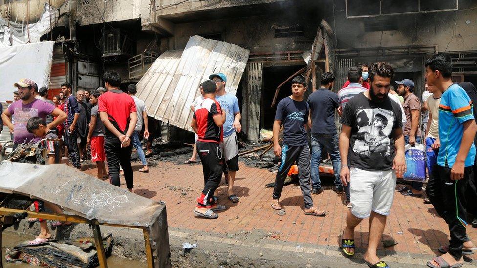 People gather at the scene of a car bomb attack in Baghdad's mainly Shia district of Sadr City