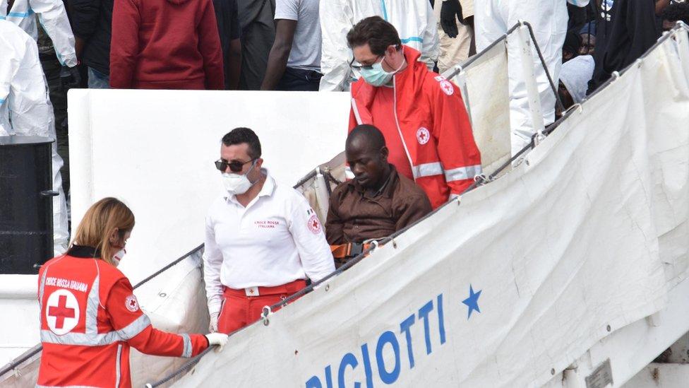 A migrant is helped off the coast guard ship "Diciotti" after arriving at Catania Port, Italy, 13 June 2018