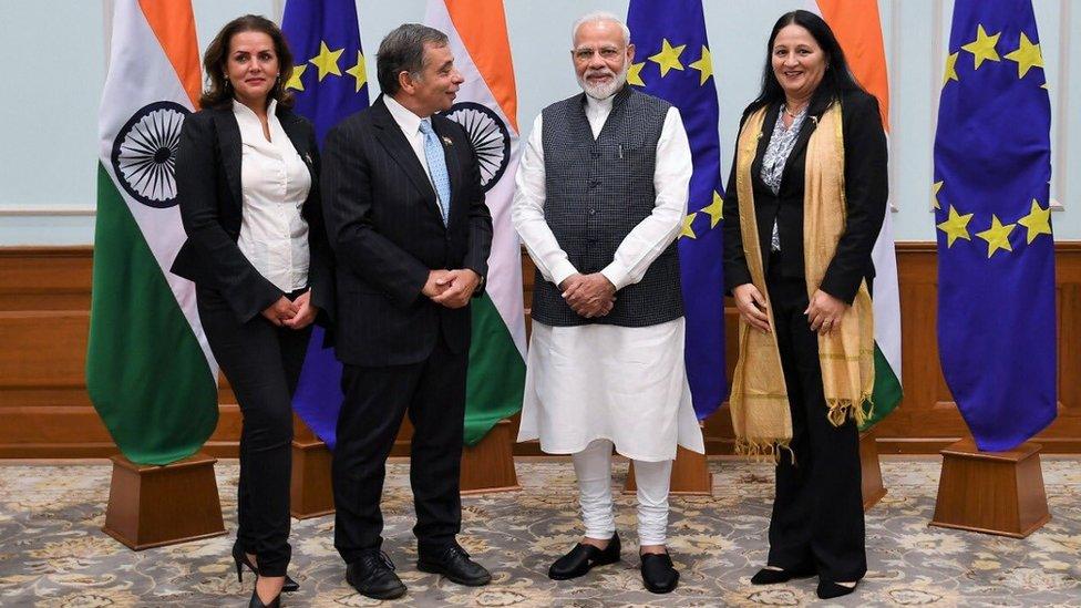 Delegation pose for picture in front of flags