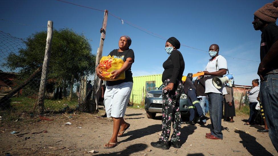 A township resident carries a food package handed out by a non governmental organisation during a 21-day nationwide lockdown aimed at limiting the spread of the coronavirus disease