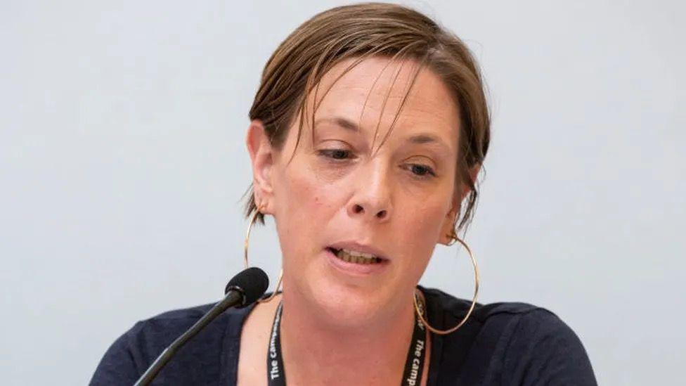 Jess Phillips wearing gold hoop earrings and a blue top