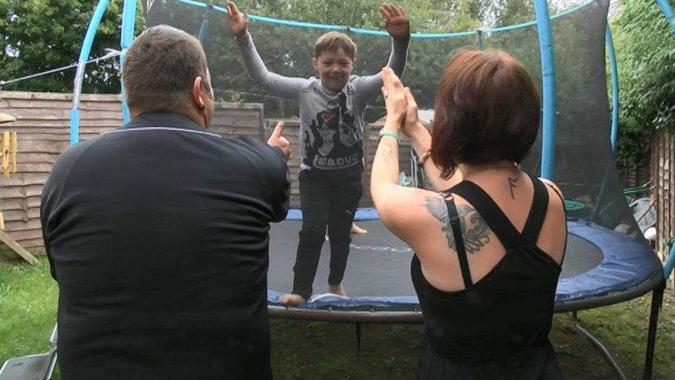 Leon Cronk on his trampoline with his parents standing nearby