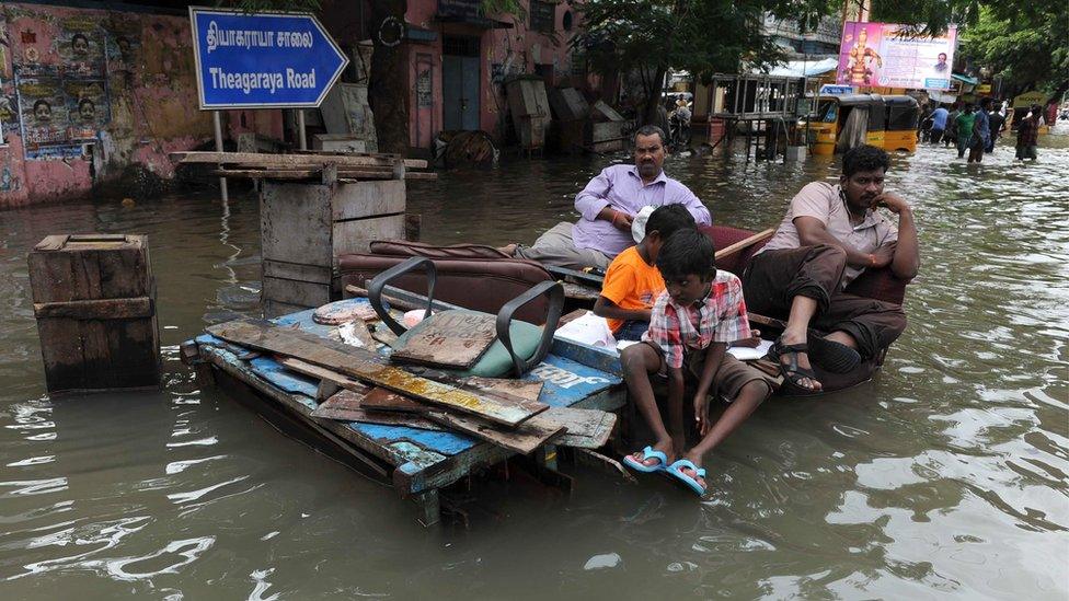 Indian residents sit on wooden pallets in floodwaters in Chennai