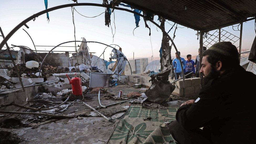 A man sits in a tent damaged by a missile attack on the Qah camp for displaced people in Idlib province, Syria (21 November 2019)