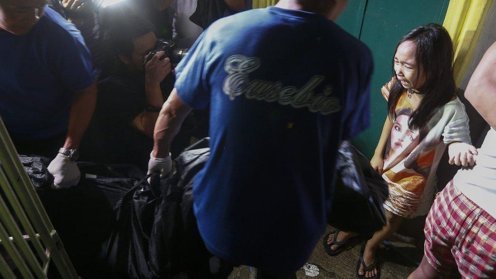 body of a Filipino man, who was killed in a reported police illegal drugs raid, is carried away