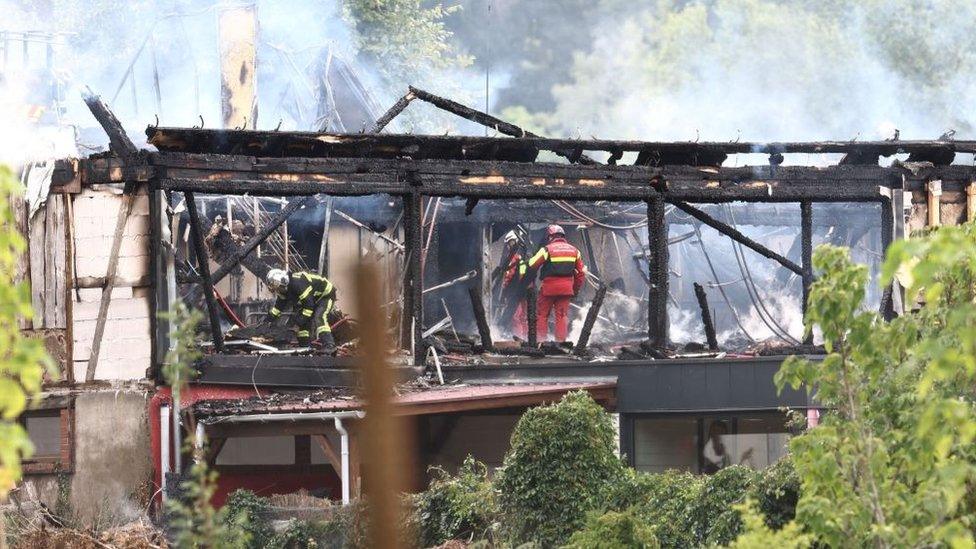 Firefighters inspect a burnt building