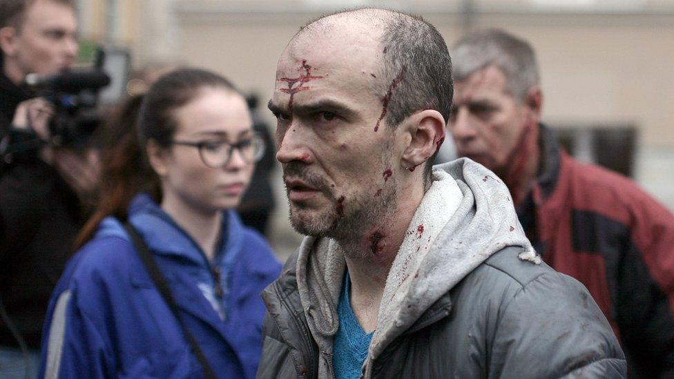 An injured man is helped by medics outside Tekhnologichesky Institut metro station in St Petersburg 3 April 2017