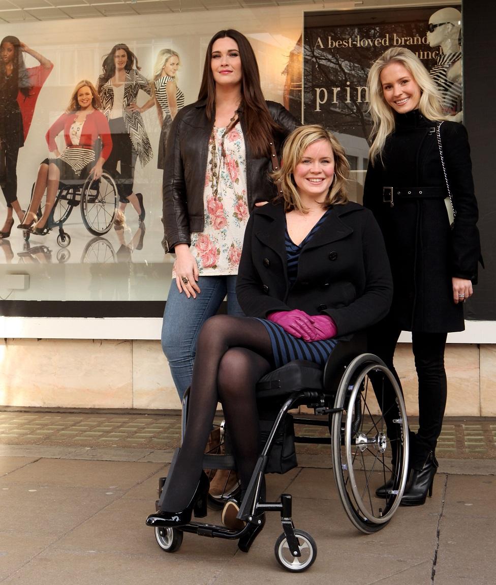 Three models stand in front of a window display