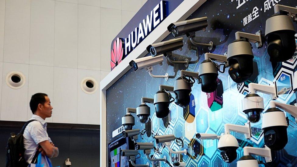 A man stands in front of a Huawei display of security cameras