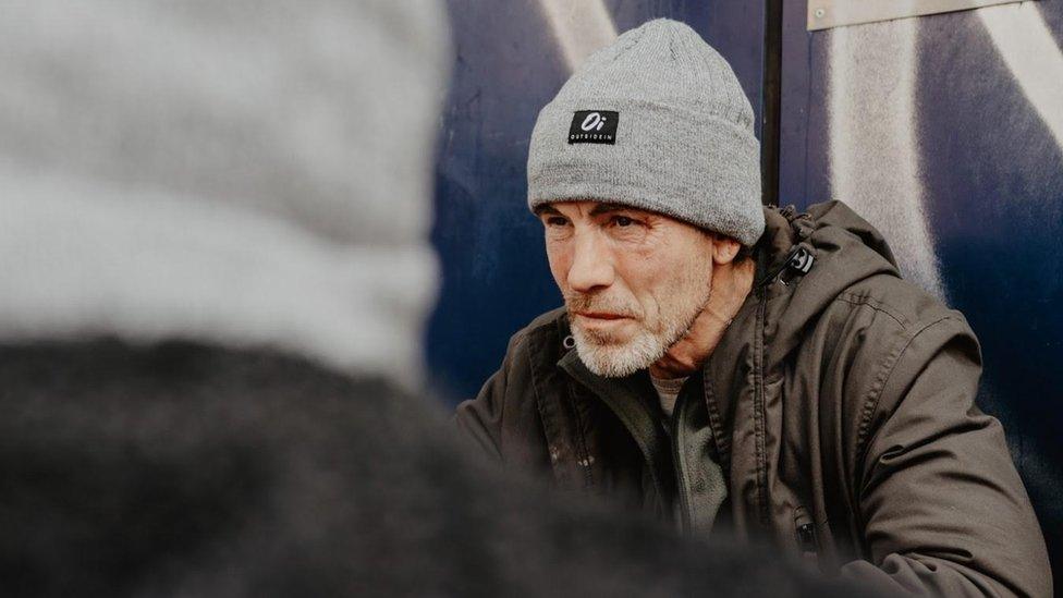 Homeless man wearing Outside In hat