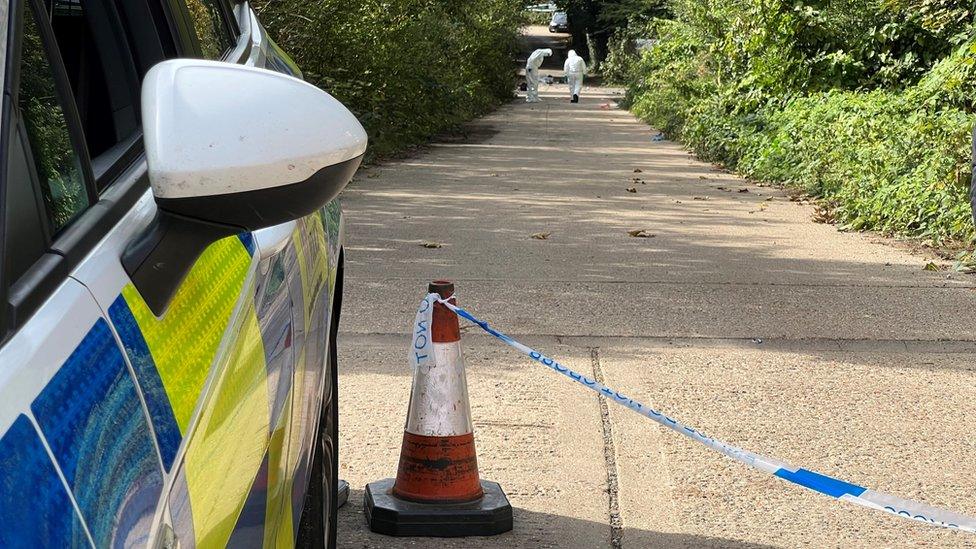 Distillery Lane, Colchester, cordoned off by police tape, with crime scene investigators looking at the ground