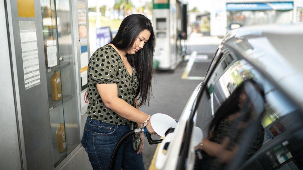 Woman filling up car at petrol pump