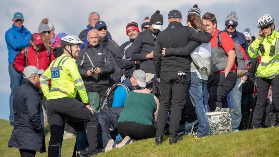 Police and first aiders attending to spectator